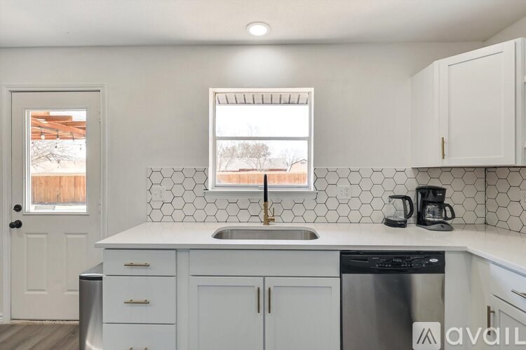 A kitchen with white cabinets and a black dishwasher.