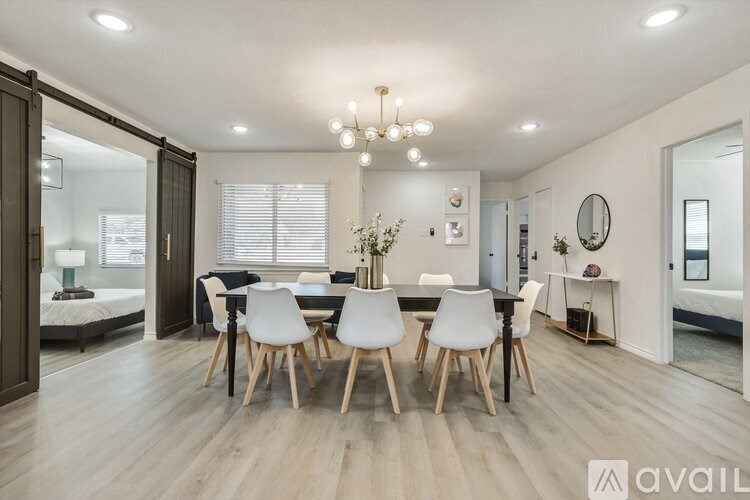 A modern dining room with a black table and white chairs.