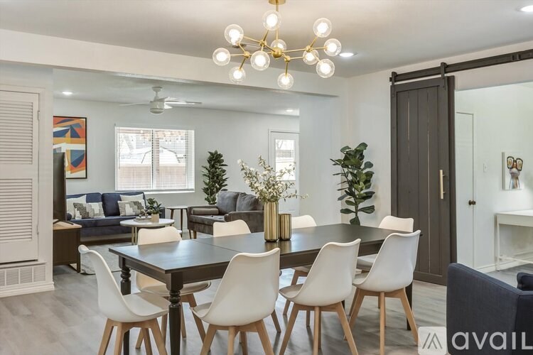 A modern dining room with a black table and white chairs.