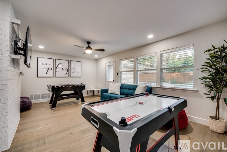 A pool table is in the middle of a room with a couch and a TV.