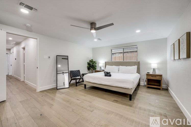 A bedroom with a bed, chair, and a plant.