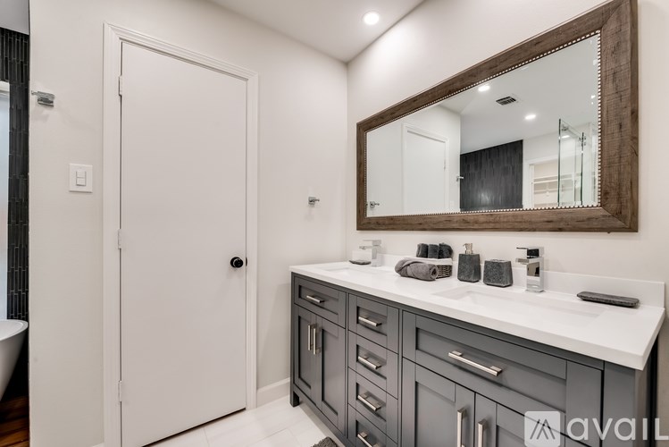 A bathroom with a white door, a mirror above a sink, and a white counter.