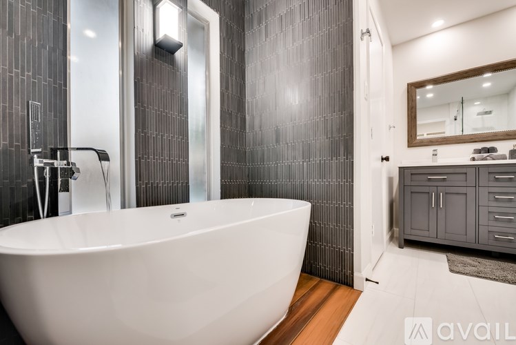 A modern bathroom with a white bathtub and wooden floors.