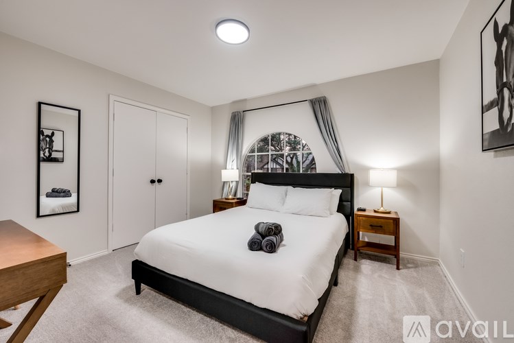 A bedroom with a large bed, a nightstand, and a window with a canopy.