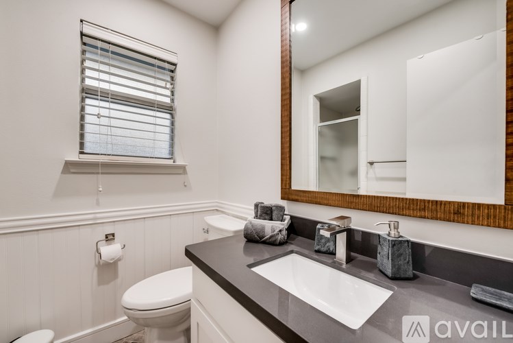 A bathroom with a white toilet, a sink, and a mirror.