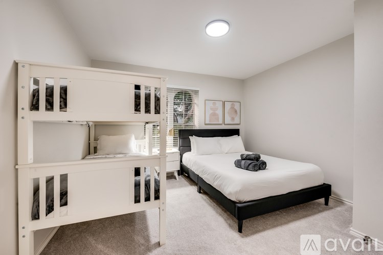 A bedroom with a white bunk bed and a black bed.