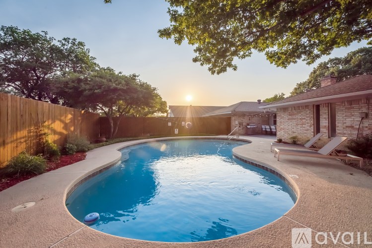 A swimming pool surrounded by a concrete patio and a wooden fence.