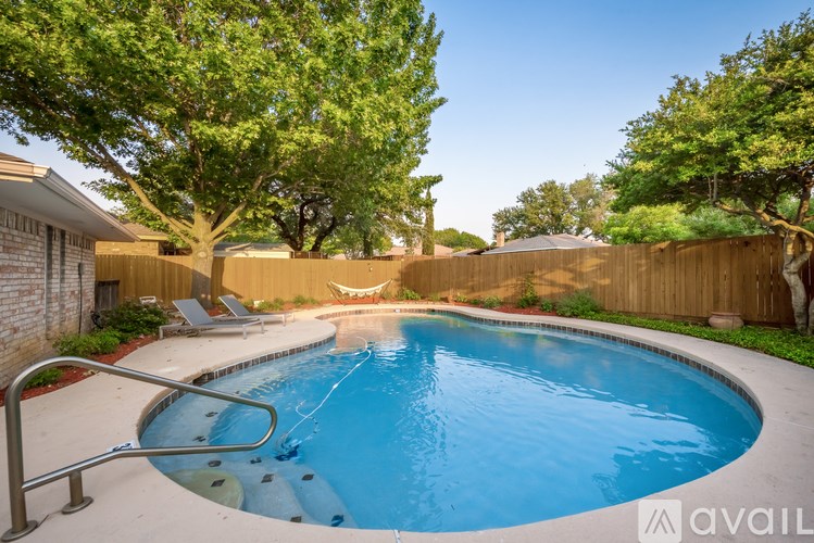 A small residential pool surrounded by a wooden fence and trees.