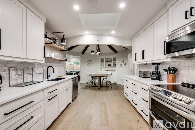A modern kitchen with white cabinets and a wooden floor.