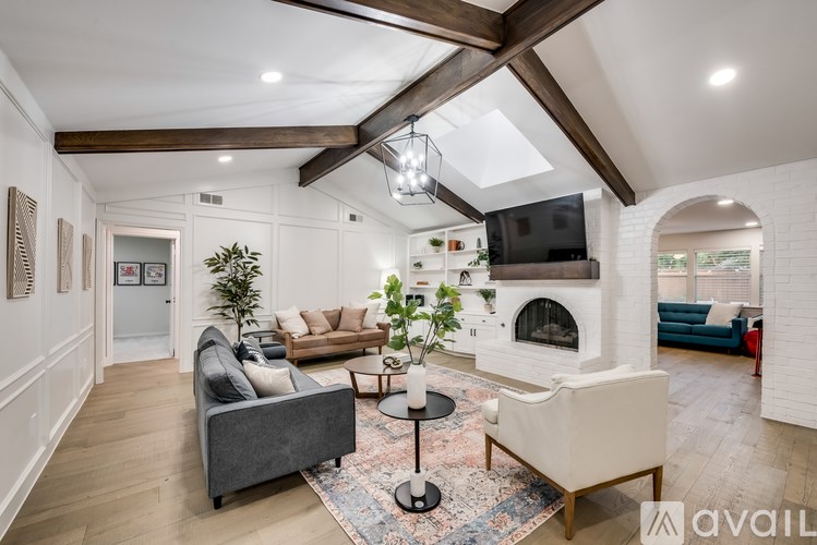 A living room with a grey couch, a white armchair, a black coffee table, and a fireplace.