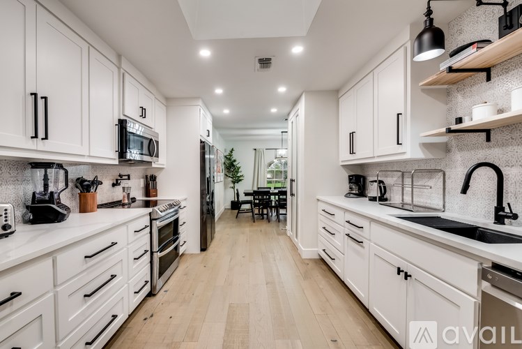 A modern kitchen with white cabinets and wooden floors.