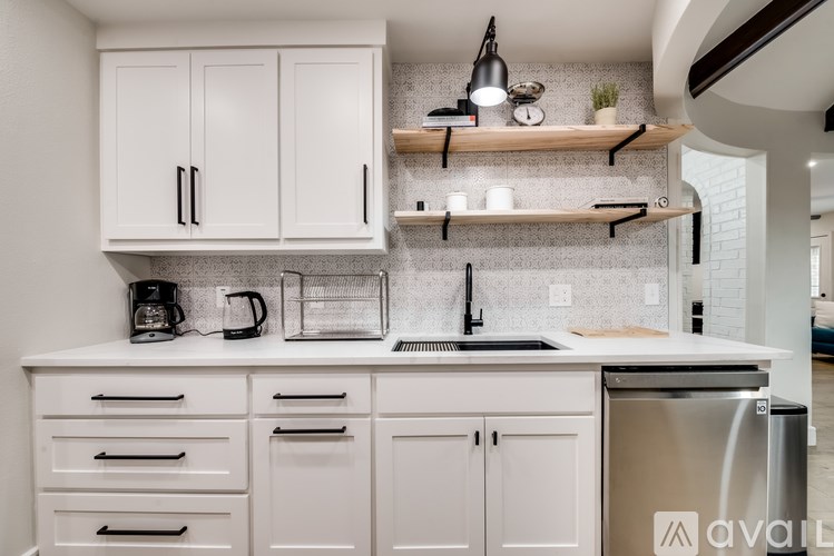 A kitchen with white cabinets and a stainless steel dishwasher.