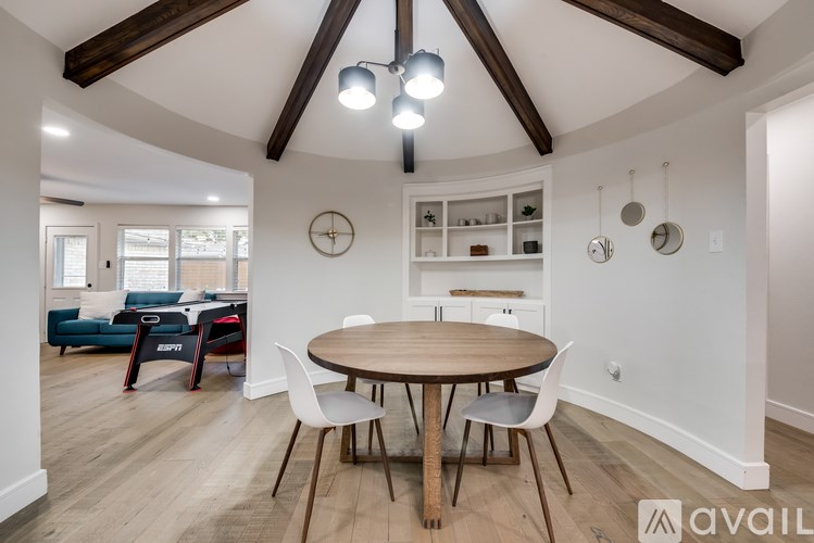 A modern dining room with a round wooden table and white chairs.