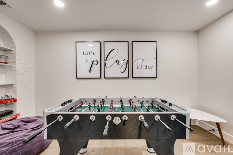A foosball table in a room with two framed pictures on the wall.