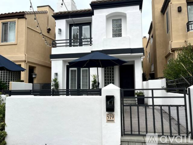 A white house with black railings and a black umbrella.