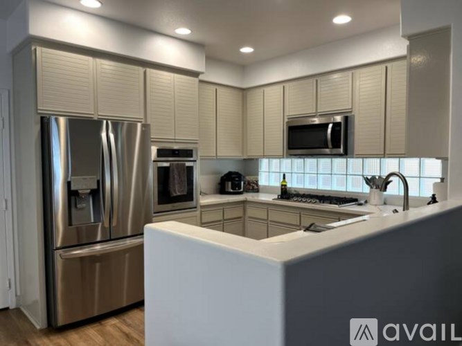 A modern kitchen with a stainless steel refrigerator and a white island.