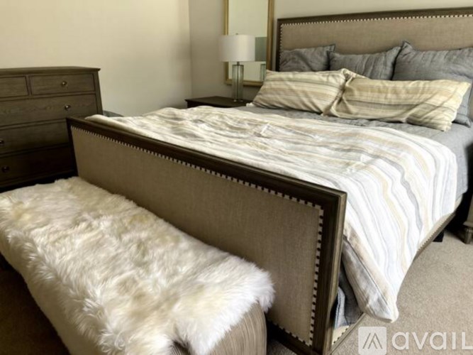 A bed with a white pillow and a grey blanket.