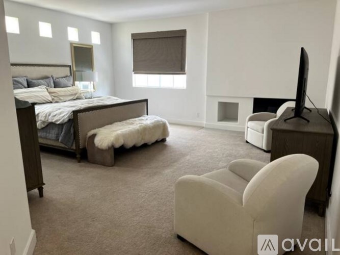 A bedroom with a large bed, a chair, and a television.