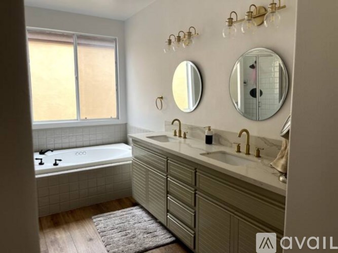A bathroom with a tub, sink, and mirror.