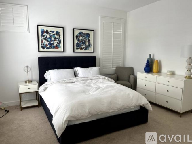 A bedroom with a black headboard and white bedding.