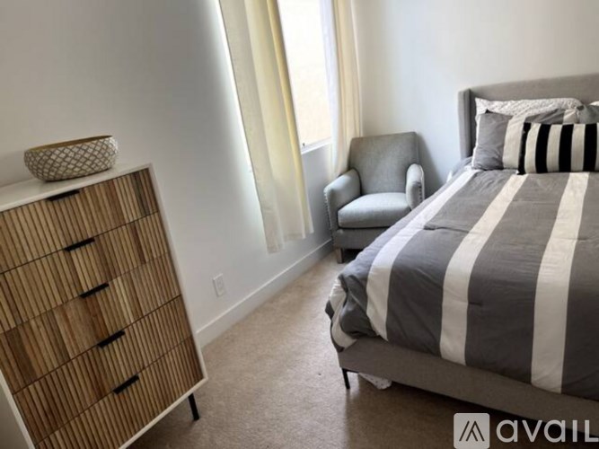 A bedroom with a bed, chair, and dresser.