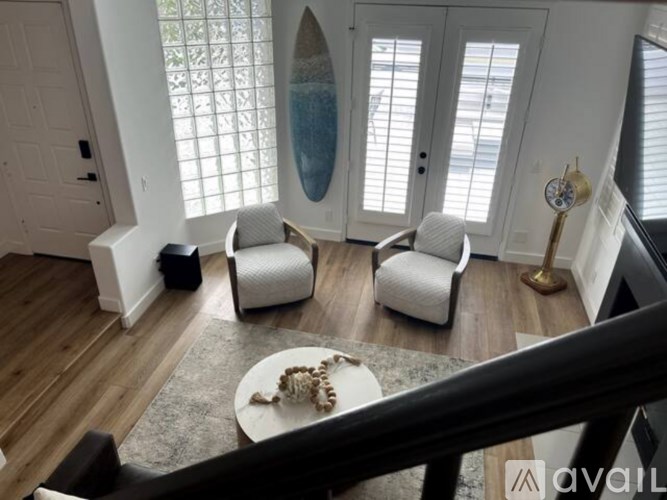 A living room with a white couch, a coffee table, and a large window with a view of the ocean.