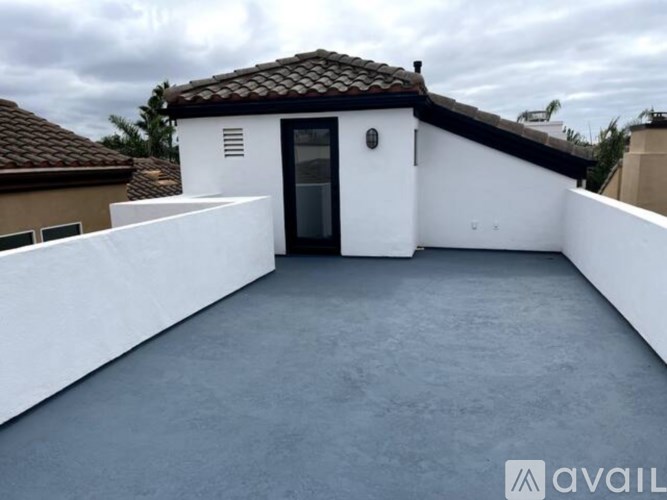 A white house with a black door and windows is surrounded by a white wall.