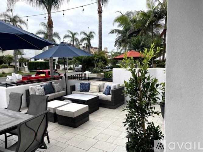 A patio with a table, chairs, and umbrellas.