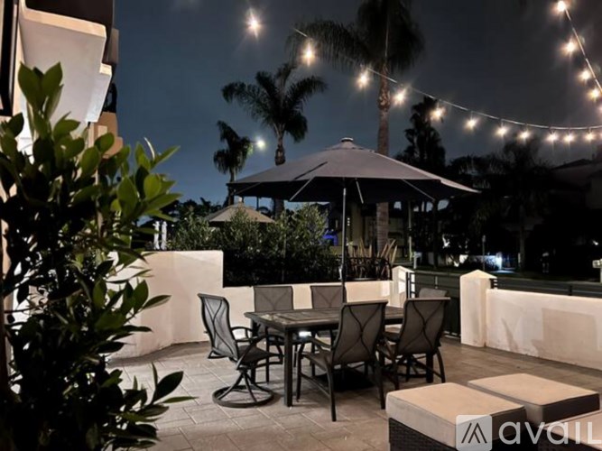 A patio with a table and chairs under a canopy with string lights.