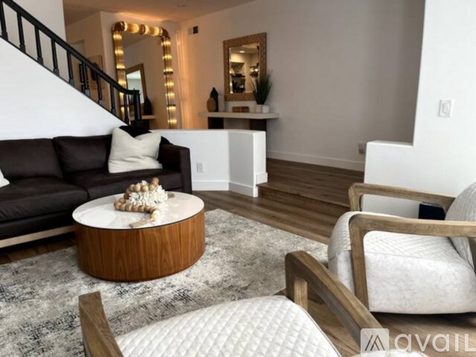 A living room with a brown couch, a round wooden coffee table, and a white chair.