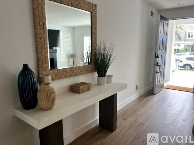 A mirror on a console table with a vase and a plant on it.