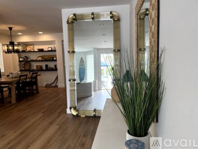 A living room with a dining table and chairs, a potted plant, and a mirror on the wall.