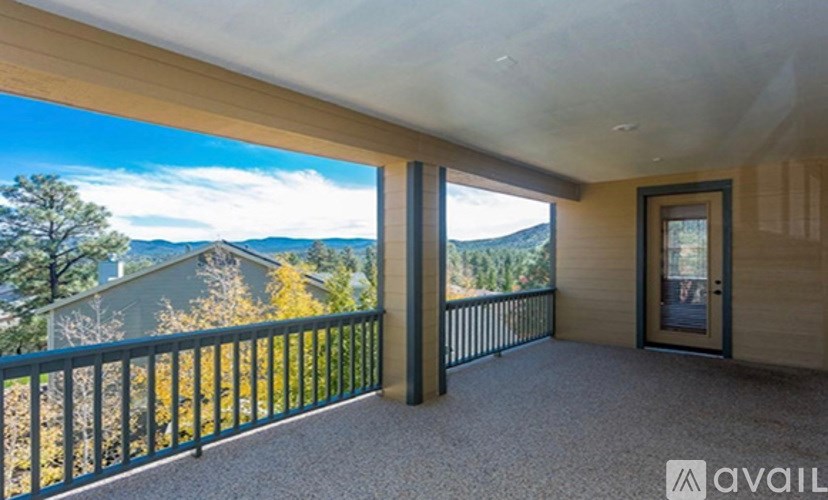 A balcony with a view of the mountains and trees.