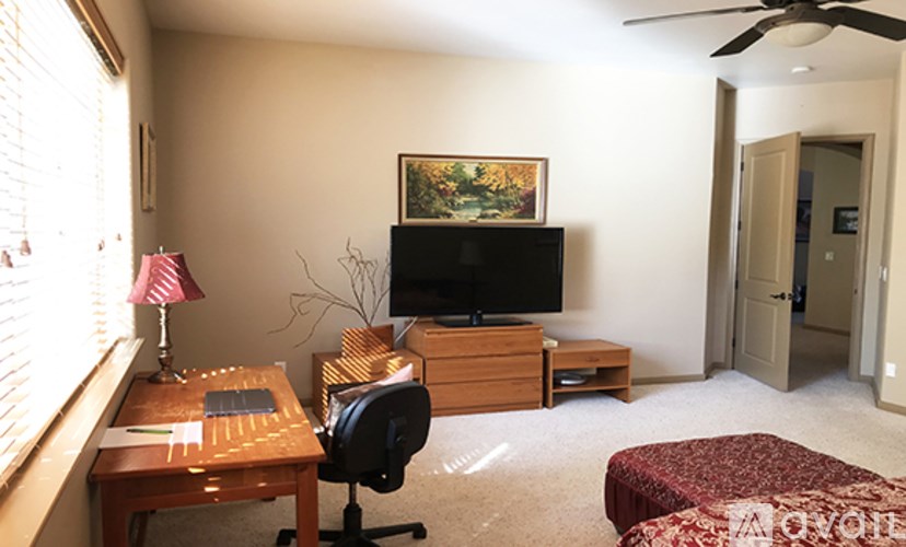 A living room with a television, chair, and a table with a laptop on it.