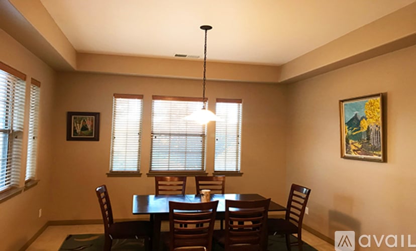 A dining room with a table set for two and a chandelier hanging from the ceiling.