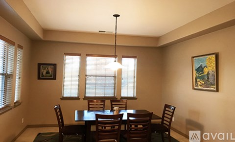 A dining room with a table set for two and a chandelier hanging from the ceiling.