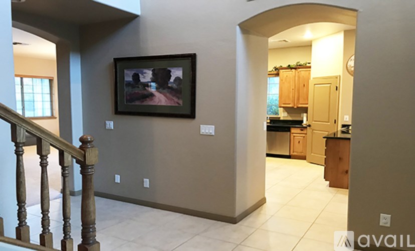 A living room with a staircase and a painting on the wall.