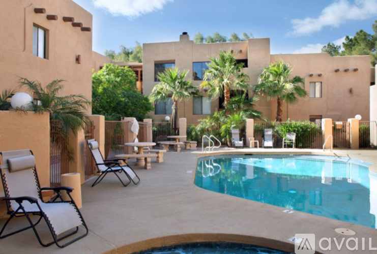 A pool area with lounge chairs and a building in the background.