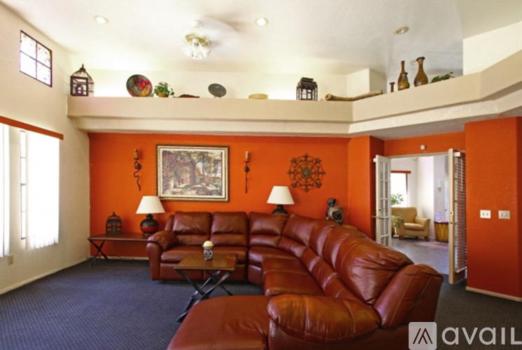 A living room with orange walls and a red leather couch.