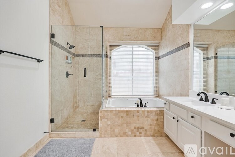 A bathroom with a walk-in shower, a bathtub, and a window.