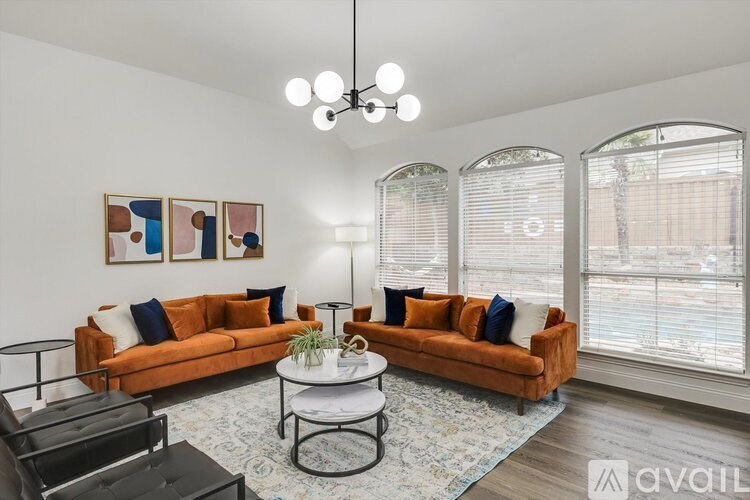 A living room with a large window, two orange couches, and a coffee table.