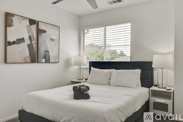 A bedroom with a large bed and two lamps.