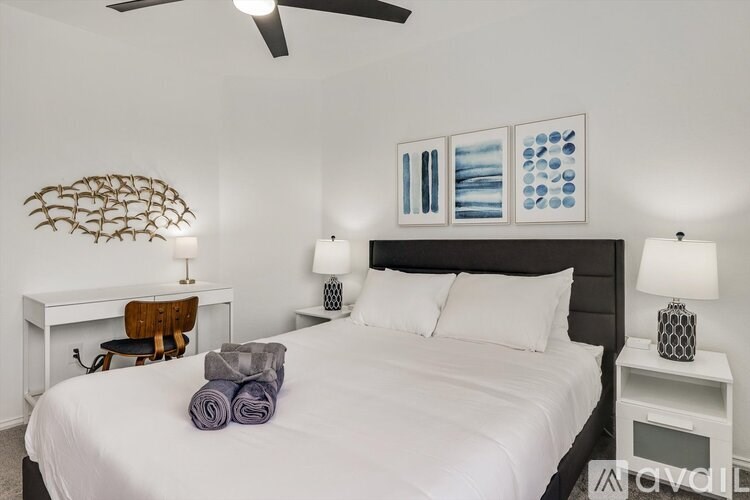 A bedroom with a white bed and a ceiling fan.