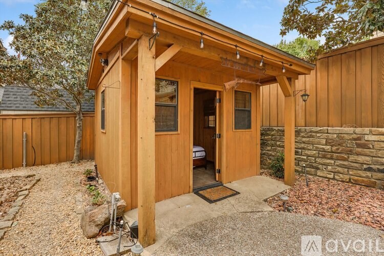 A wooden cabin with a porch and a door is available for rent.