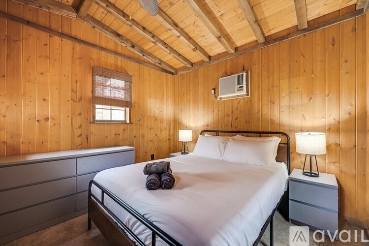A bedroom with a bed, nightstand, and window.
