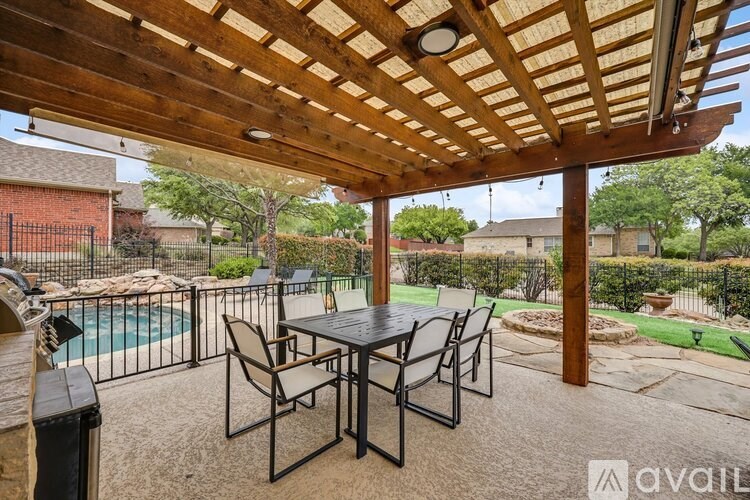 A patio with a table and chairs under a wooden pergola.