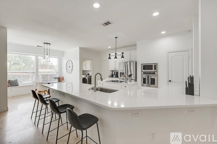 A modern kitchen with white countertops and black barstools.