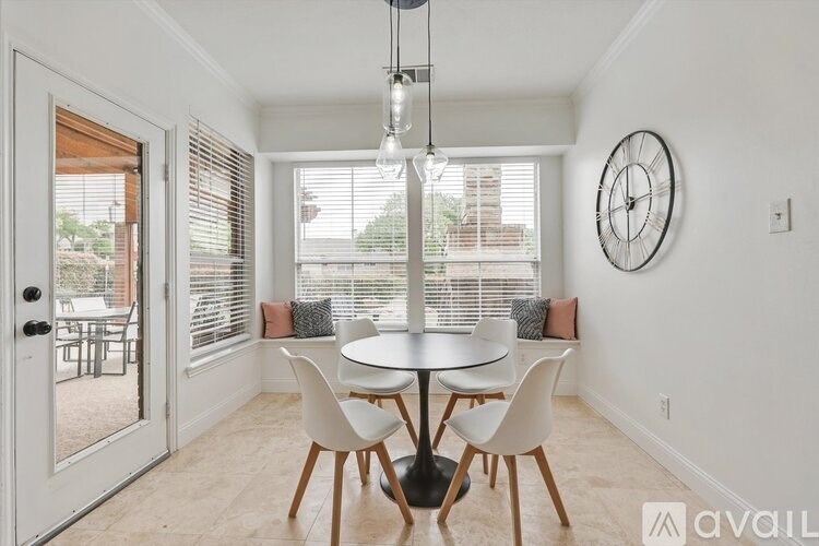 A dining room with a table and chairs and a clock on the wall.