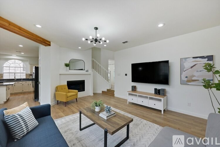 A living room with a blue couch, a yellow chair, a fireplace, and a television.