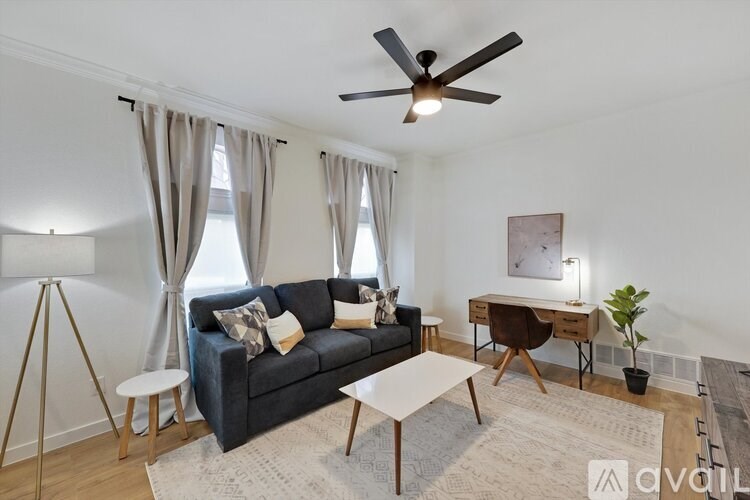 A living room with a grey couch, a white coffee table, a brown chair, a small potted plant, and a painting on the wall.